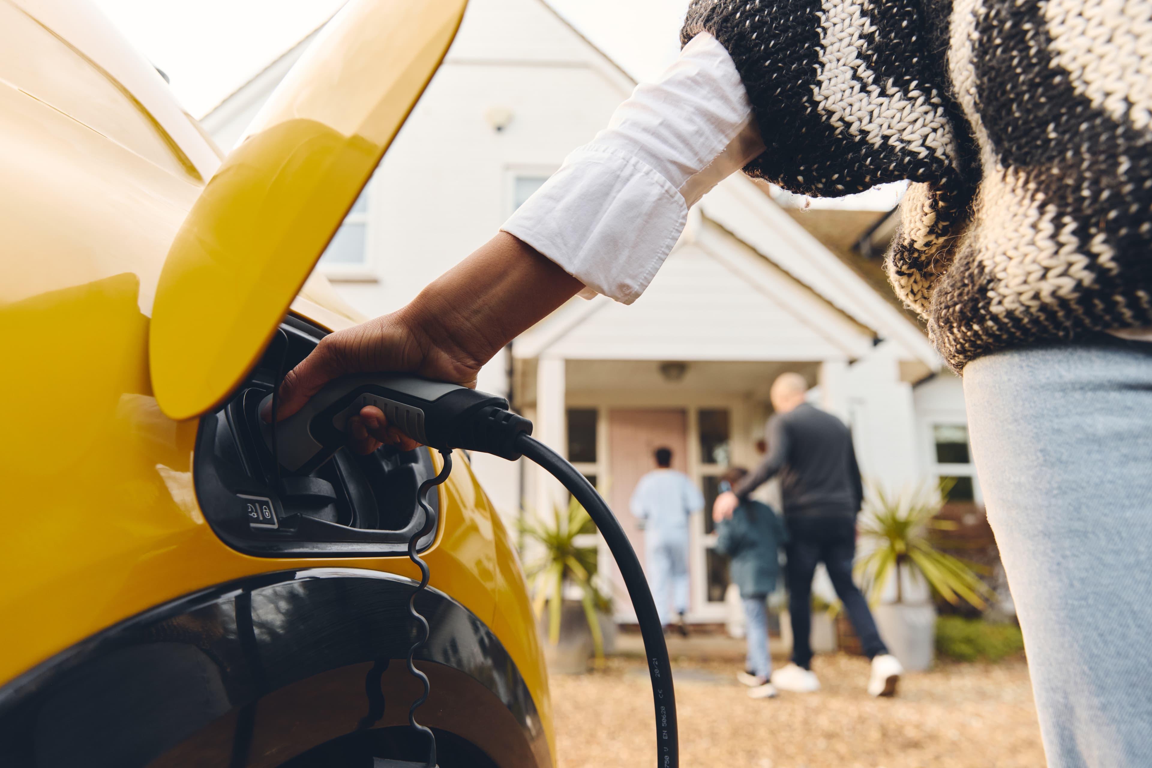 Person charging an electric vehicle at home